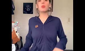 Youthful beauty dances seductively in tight shorts, teasing alluring curves with playful energy.